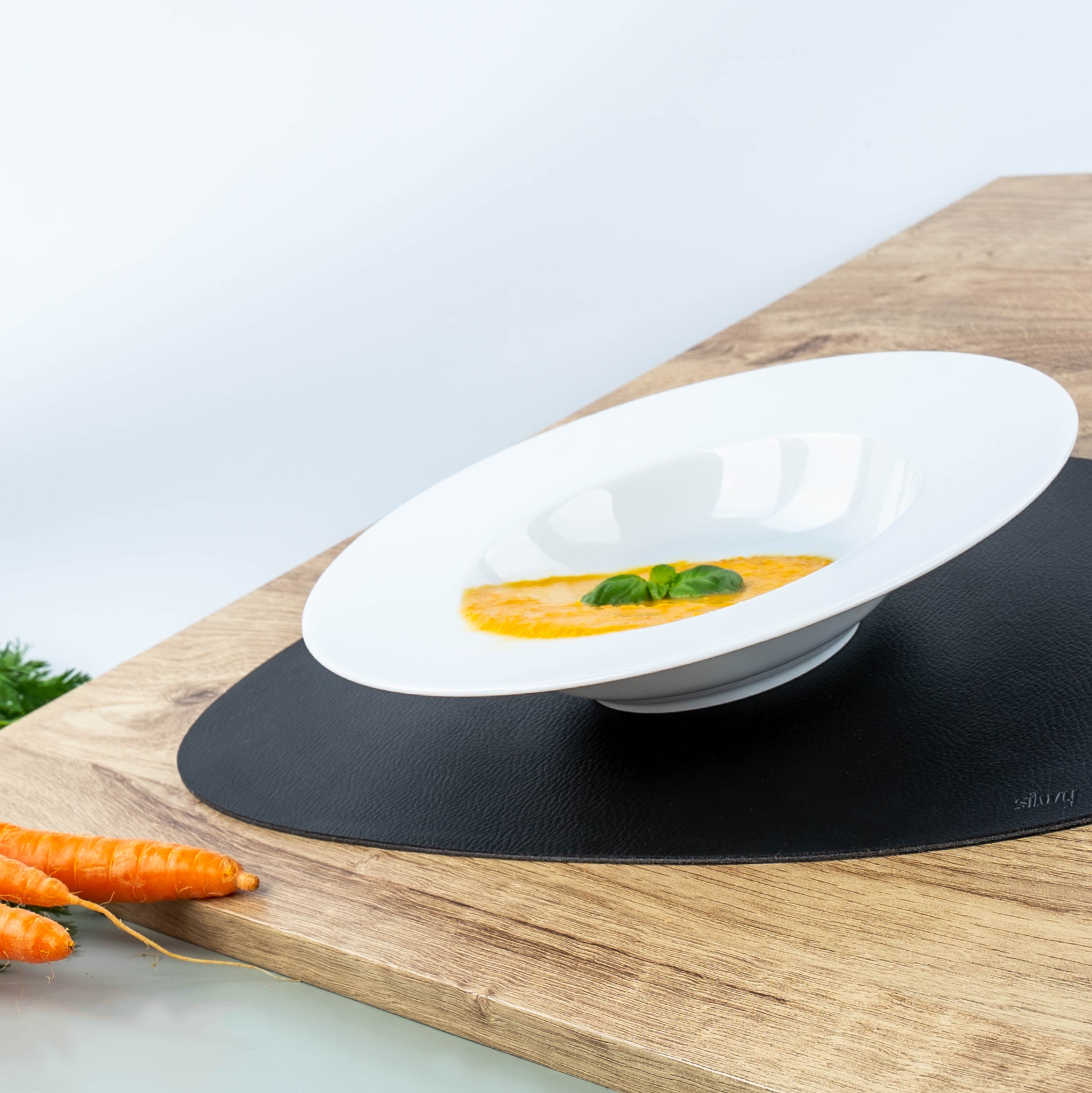 Magnet-Porzellan-Gourmetteller mit Karottensuppe und Basilikum auf Platzset