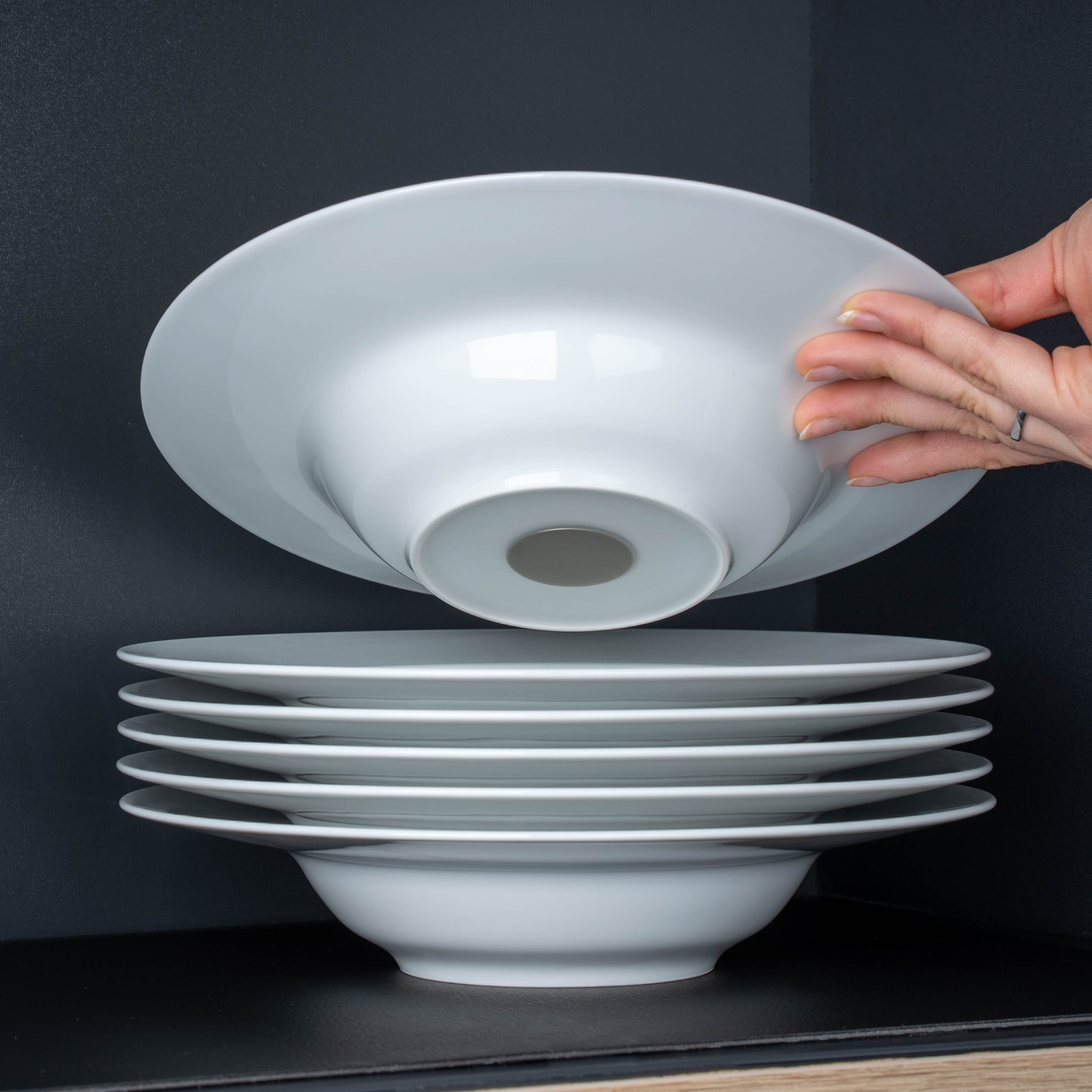 Magnet-Porzellan-Gourmetteller mit integriertem Magneten im Boden aufeinandergestapelt auf Metall-Matte in schwarz im Regal 